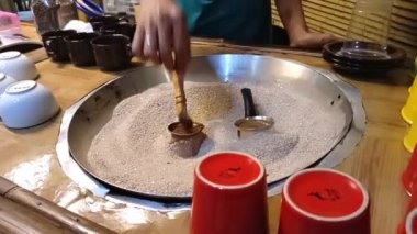 Kum üzerinde bir Türk çerezinde kahve yapma süreci. Bakır kahve kaplarında geleneksel Türk kahvesi pişirmek. Seçici odaklanma, yakın plan. Konsept kahve molası, turizm ve seyahat.