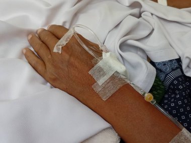 Hastanın eline serum yoluyla ilaç veren bir hemşire..