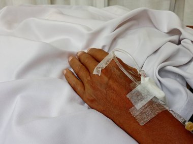 Hastanın eline serum yoluyla ilaç veren bir hemşire..