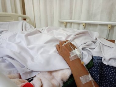 Hastanın eline serum yoluyla ilaç veren bir hemşire..