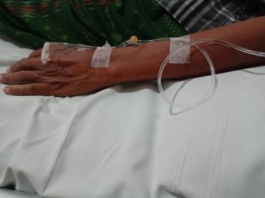 Hastanın eline serum yoluyla ilaç veren bir hemşire..