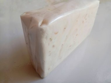 Tempe ya da tempeh beyaz plastiğe sarılmış geleneksel Endonezya yemekleri. Mayalanmış soya fasulyesinden yapılmış. İzole edilmiş beyaz arka plan.