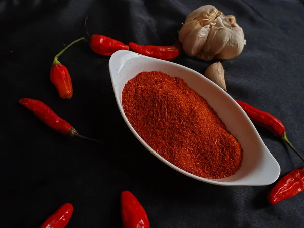 辣椒粉是一种调味的调料 用白色碗中的辣椒和黑色底色的红辣椒混合而成 — 图库照片