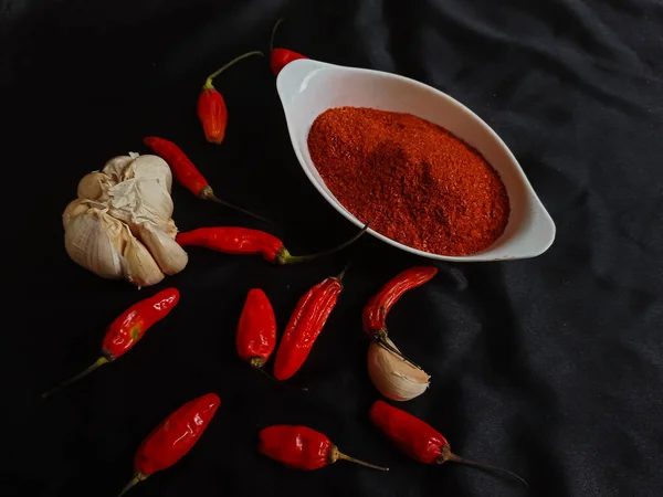 辣椒粉是一种调味的调料 用白色碗中的辣椒和黑色底色的红辣椒混合而成 — 图库照片