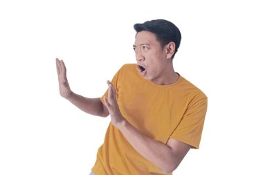 Turuncu tişört giyen Asyalı bir adamın portresi, beyaz bir arka planda izole edilmiş, açık avuçlarla şaşkınlık ve şoku ifade ediyor..