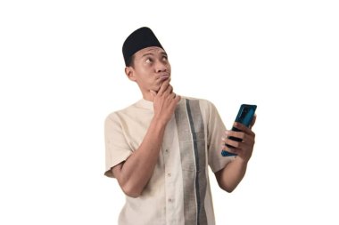 Asyalı Müslüman bir adam akıllı bir telefon tutuyor, Happy internetten özel bir hediye alıyor, mutlu Asyalı Müslüman adam cep telefonunu tutuyor ve işaret ediyor. Ramazan konsepti. Şaşırdım.