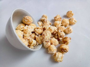 Beyaz arka planda izole edilmiş kasedeki lezzetli peynirli patlamış mısır. Duvar kağıdı, afiş, metin için kopya alanı olan başlık. Fast food, sinema, sinema ve eğlence konsepti.