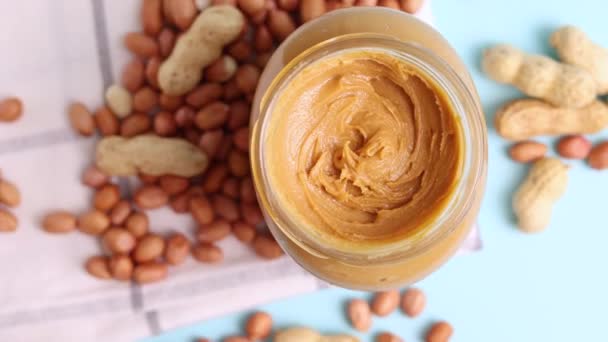 Erdnussbutter Und Rohe Erdnüsse Auf Farbigem Hintergrund Hochwertiges Foto — Stockvideo