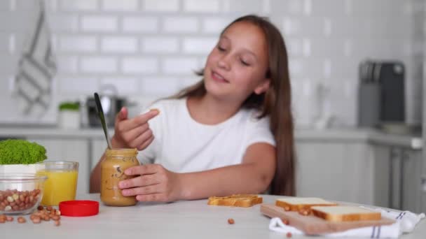 Dziewczyna Dobrym Nastroju Robi Kanapkę Masłem Orzechowym Kuchni Wysokiej Jakości — Wideo stockowe
