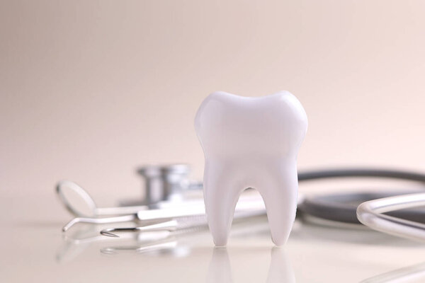 Dentistry concept. Model of a tooth and dental instruments on a colored background with space for text. . High quality photo