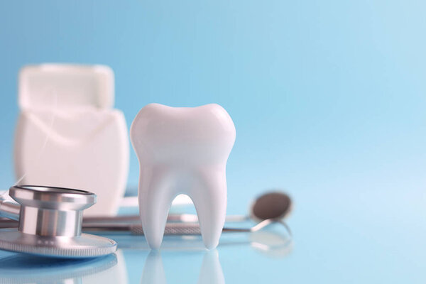 Dentistry concept. Model of a tooth and dental instruments on a colored background with space for text. . High quality photo