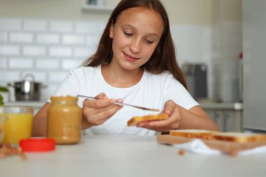 Keyfi yerinde bir kız mutfakta fıstık ezmeli sandviç yapıyor. Yüksek kalite fotoğraf