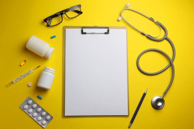 Doktor masası üst görünümü. Renkli arka planda farklı doktor aksesuarları. Haplar, gözlükler, steteskop ve defter. - Evet. Yüksek kalite fotoğraf