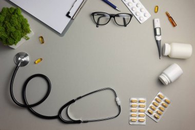 Doctors desk top view. Set of different doctor accessories on a colored background. Pills, glasses, stethoscope and notebook. . High quality photo clipart