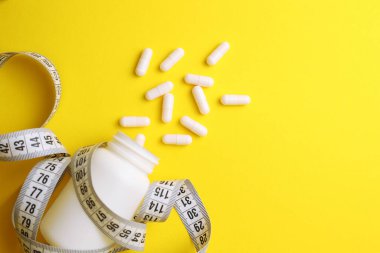 Renkli arka planda santimetre bant ve haplar. Mesaj için yer var. Kilo verme, diyet yapma, yağ yakma, sağlıklı beslenme kavramı. Minimalizm. - Evet. Yüksek kalite fotoğraf