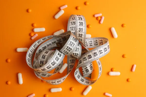 Renkli arka planda santimetre bant ve haplar. Mesaj için yer var. Kilo verme, diyet yapma, yağ yakma, sağlıklı beslenme kavramı. Minimalizm. - Evet. Yüksek kalite fotoğraf