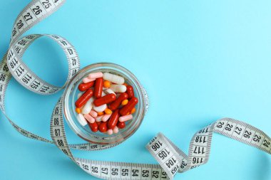 Renkli arka planda santimetre bant ve haplar. Mesaj için yer var. Kilo verme, diyet yapma, yağ yakma, sağlıklı beslenme kavramı. Minimalizm. - Evet. Yüksek kalite fotoğraf