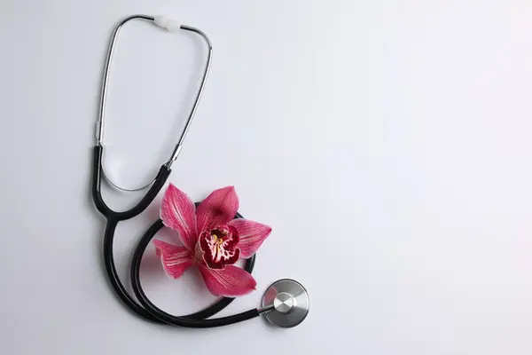 Orchidee Und Stethoskop Auf Farbigem Hintergrund Draufsicht Symbol Der Frauengesundheit — Stockfoto
