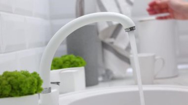 Bir kız mutfak musluğundan bardağa temiz su döker. Saf su. Yüksek kalite 4k görüntü