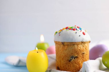 An Easter cake is adorned with icing, decorations, colored eggs, and lit candles, creating a festive atmosphere