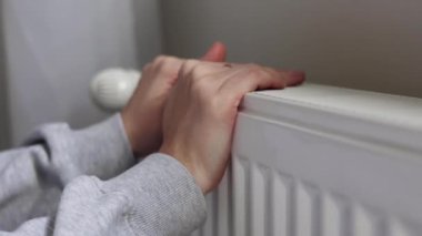 Bir kız odadaki radyatörün ısıtmasını kontrol ediyor. Yüksek kalite 4k görüntü