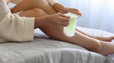 Bir kız, odanın içinde balmumuyla bacaklarındaki istenmeyen tüyleri alıyor. Yüksek kalite 4k görüntü