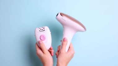 İstenmeyen vücut kıllarını evde yoketmek için modern bir epilatör ve kadınların elinde renkli bir arka planda mekanik bir epilatör. Yüksek kalite 4k görüntü