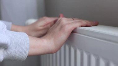 Bir kız odadaki radyatörün ısıtmasını kontrol ediyor. Yüksek kalite 4k görüntü
