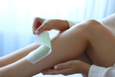 Bir kız, odanın içinde balmumuyla bacaklarındaki istenmeyen tüyleri alıyor. Yüksek kalite 4k görüntü