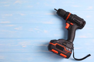 Üzerinde çeşitli matkap uçları bulunan kablosuz matkap mavi ahşap bir yüzeye yerleştirilir. DIY projeleri için mükemmel.