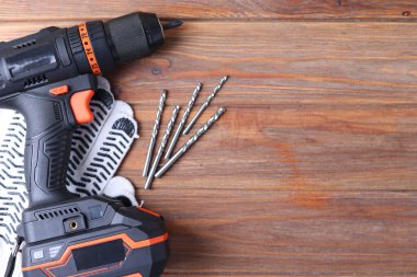 Üzerinde çeşitli matkap uçları bulunan kablosuz matkap mavi ahşap bir yüzeye yerleştirilir. DIY projeleri için mükemmel.