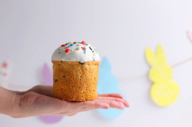 An Easter cake is adorned with icing, decorations, colored eggs, and lit candles, creating a festive atmosphere