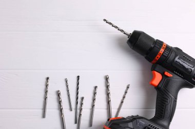 Üzerinde çeşitli matkap uçları bulunan kablosuz matkap mavi ahşap bir yüzeye yerleştirilir. DIY projeleri için mükemmel.