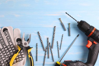 Üzerinde çeşitli matkap uçları bulunan kablosuz matkap mavi ahşap bir yüzeye yerleştirilir. DIY projeleri için mükemmel.