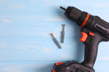 Üzerinde çeşitli matkap uçları bulunan kablosuz matkap mavi ahşap bir yüzeye yerleştirilir. DIY projeleri için mükemmel.
