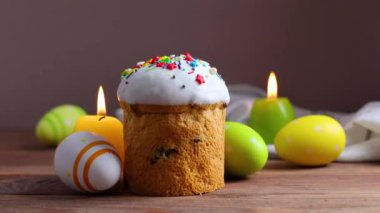 An Easter cake is adorned with icing, decorations, colored eggs, and lit candles, creating a festive atmosphere