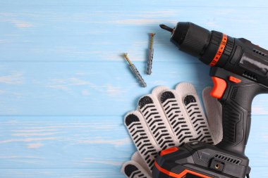 Üzerinde çeşitli matkap uçları bulunan kablosuz matkap mavi ahşap bir yüzeye yerleştirilir. DIY projeleri için mükemmel.