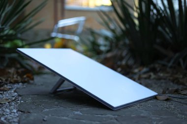 Çağdaş bir güneş paneli, yeşilliklerin arasında zarif bir şekilde konumlandırılmış, temiz enerji teknolojisi sergiliyor..