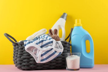 Katlanmış giysiler, plastik ördek ve pastel arka planda deterjan içeren şirin bebek çamaşırları sahnesi..
