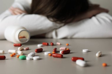 Halıya dağılmış haplarla potansiyel bir aşırı dozu tasvir eden dramatik bir sahne umutsuzluğu simgeliyor.