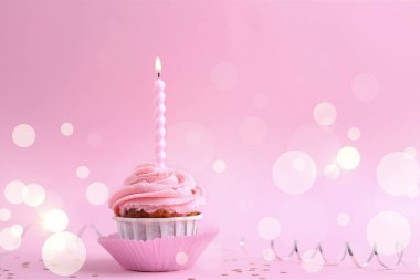 Kremalı kremalı renkli bir kek ve parlak bir mum. Neşeli kutlamalar için ideal.