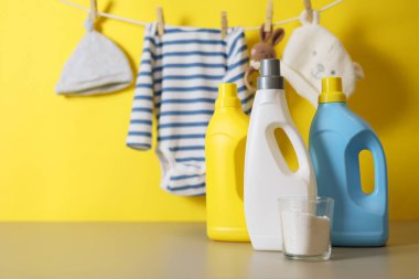 Katlanmış giysiler, plastik ördek ve pastel arka planda deterjan içeren şirin bebek çamaşırları sahnesi..