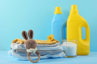 Katlanmış giysiler, plastik ördek ve pastel arka planda deterjan içeren şirin bebek çamaşırları sahnesi..