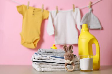 Katlanmış giysiler, plastik ördek ve pastel arka planda deterjan içeren şirin bebek çamaşırları sahnesi..