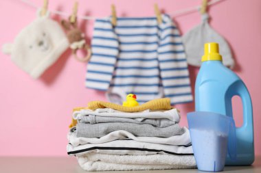Katlanmış giysiler, plastik ördek ve pastel arka planda deterjan içeren şirin bebek çamaşırları sahnesi..