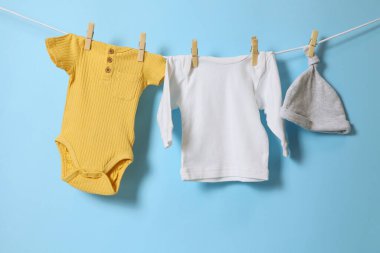 Bebek kıyafetlerinin ve sevimli aksesuarların canlı ve renkli bir görüntüsü hoş pembe bir arka planda kuruyor.