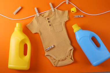 Sevimli sarı bebek tulumu çamaşır deterjanı ve bebek bakımı için ideal oyuncakla asılı.