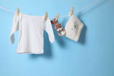 Bebek kıyafetlerinin ve sevimli aksesuarların canlı ve renkli bir görüntüsü hoş pembe bir arka planda kuruyor.