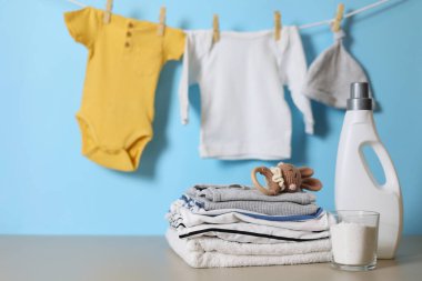 Katlanmış giysiler, plastik ördek ve pastel arka planda deterjan içeren şirin bebek çamaşırları sahnesi..