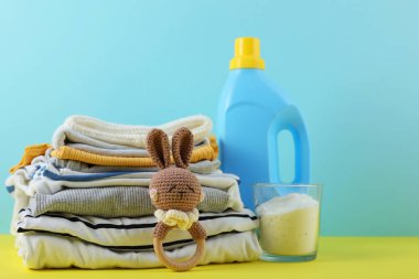 Katlanmış giysiler, plastik ördek ve pastel arka planda deterjan içeren şirin bebek çamaşırları sahnesi..